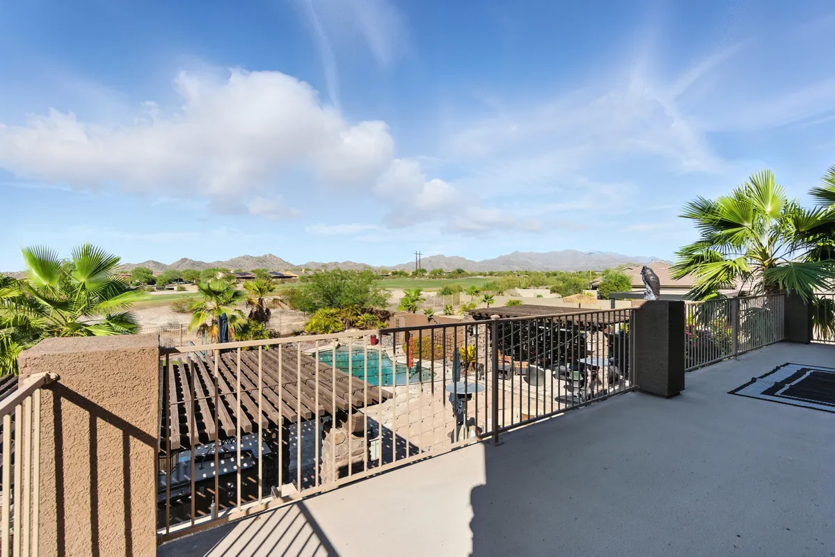 A tranquil backyard scene with a sparkling swimming pool, palm trees, mountain views, and a comfortable outdoor seating area. The inviting space suggests both relaxation and fun group activities, ideal for families.