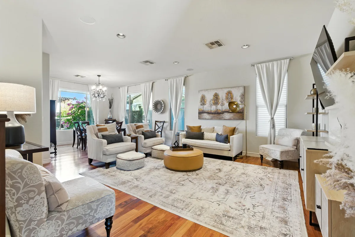 A bright living area featuring a cozy seating arrangement, expansive windows letting in abundant natural light, elegant wall art, and modern light fixtures. The space is clearly meant for both relaxation and entertaining, with a layout that encourages group interactions.